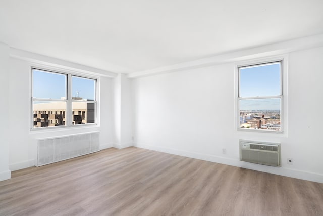 10 Huron Ave Unit 17F, Jersey City, NJ 07306 - spare room with radiator, a wall mounted AC, light wood-style flooring, and healthy amount of natural light