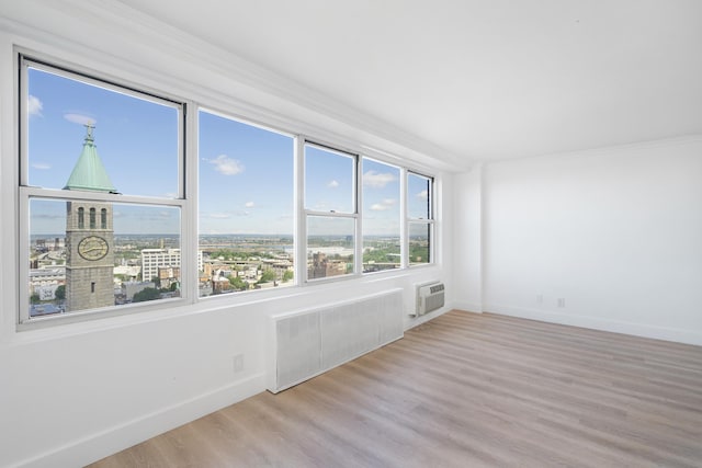 10 Huron Ave Unit 17F, Jersey City, NJ 07306 - unfurnished room with radiator heating unit, baseboards, an AC wall unit, wood finished floors, and ornamental molding