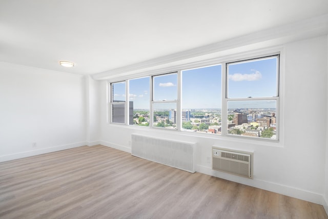 10 Huron Ave Unit 17F, Jersey City, NJ 07306 - unfurnished room with radiator, a wall mounted air conditioner, light wood-style floors, and baseboards