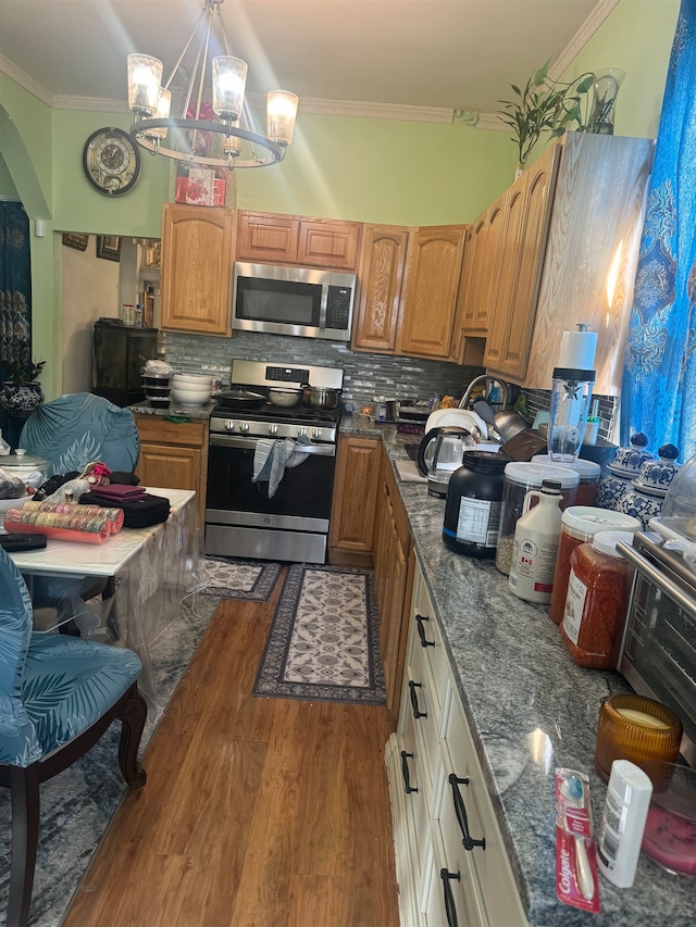 kitchen featuring appliances with stainless steel finishes, a notable chandelier, dark hardwood / wood-style floors, and crown molding