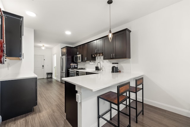 kitchen with sink, a breakfast bar area, stainless steel appliances, decorative light fixtures, and kitchen peninsula