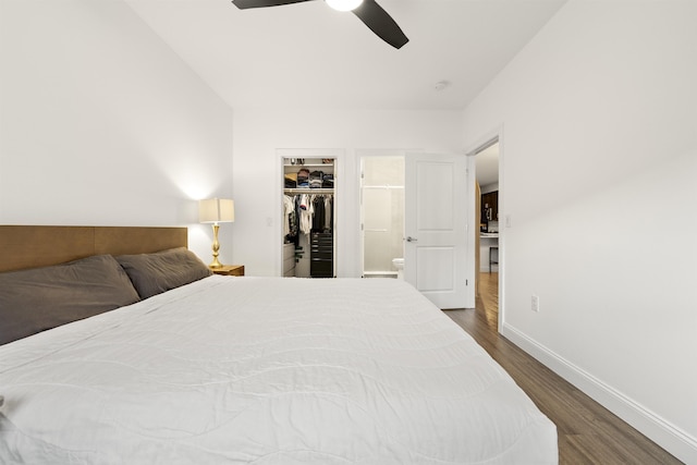 bedroom with dark wood-type flooring, a walk in closet, ensuite bath, a closet, and ceiling fan