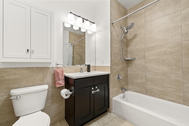 full bathroom featuring tile walls, vanity, tiled shower / bath, tile patterned floors, and toilet