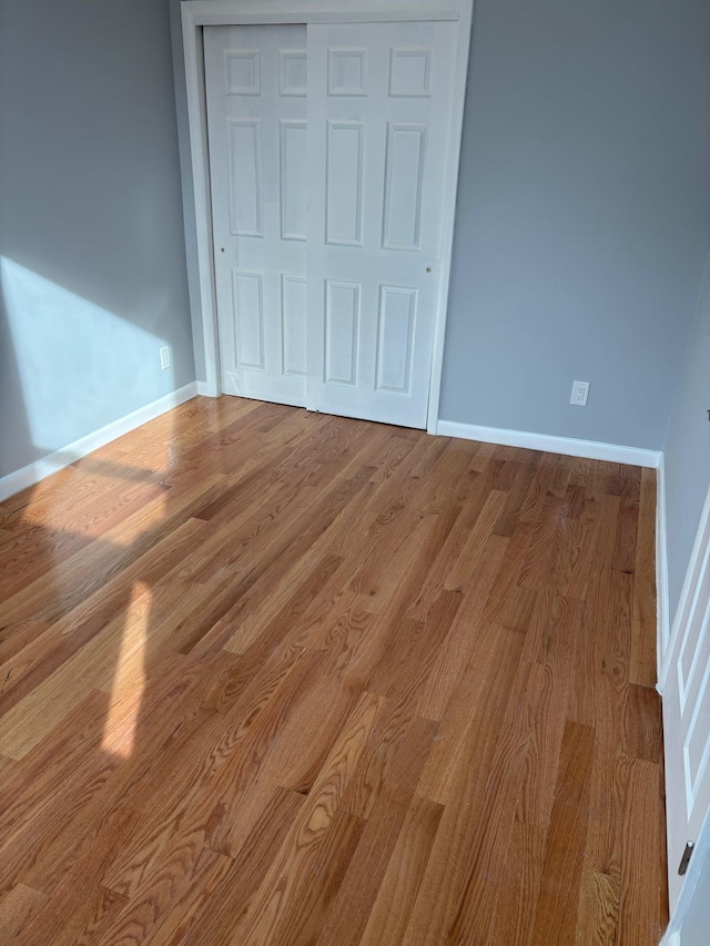 unfurnished bedroom with a closet, wood finished floors, and baseboards