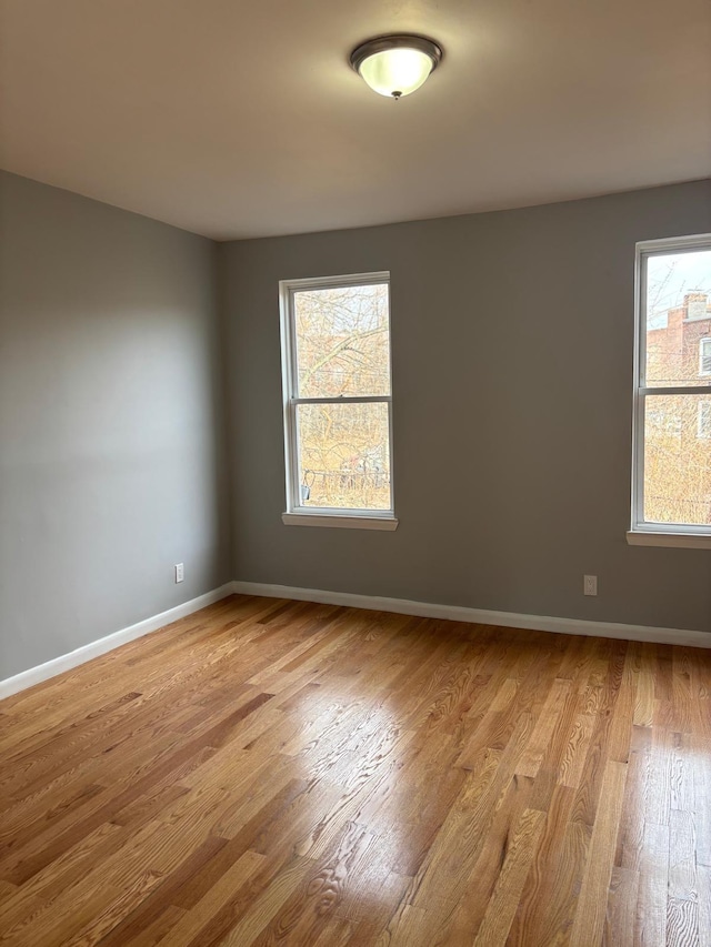 empty room featuring light wood-type flooring and baseboards