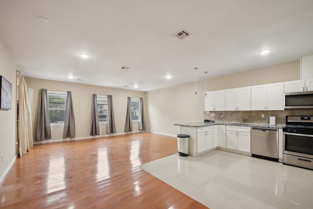 1160 Summit Ave Unit 2, Jersey City, NJ 07307 - kitchen with stainless steel appliances, backsplash, white cabinetry, open floor plan, and light stone counters