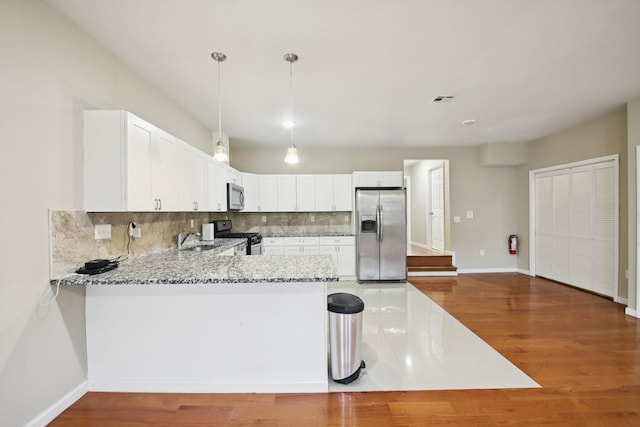 1160 Summit Ave Unit 2, Jersey City, NJ 07307 - kitchen with appliances with stainless steel finishes, light stone counters, tasteful backsplash, a peninsula, and wood finished floors