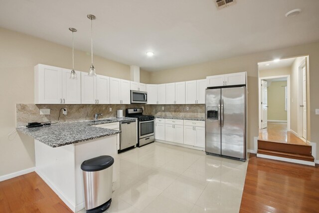 1160 Summit Ave Unit 2, Jersey City, NJ 07307 - kitchen with stainless steel appliances, decorative backsplash, light stone counters, a peninsula, and white cabinetry