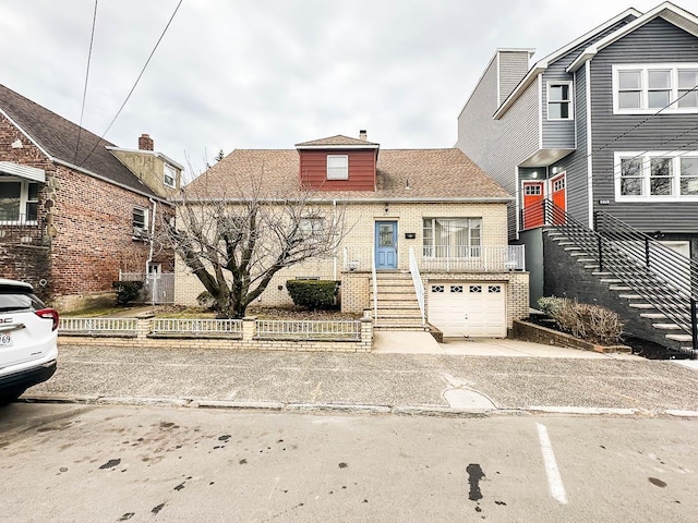 view of front of house featuring brick siding, an attached garage, stairs, a chimney, and driveway