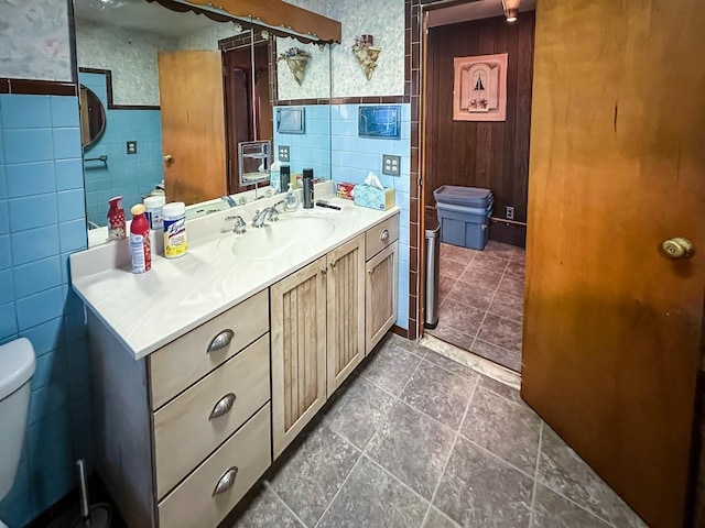 bathroom featuring a wainscoted wall, vanity, toilet, and tile walls