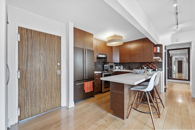 300 Newark St Unit 8G, Hoboken, NJ 07030 - kitchen featuring appliances with stainless steel finishes, a peninsula, a breakfast bar, light countertops, and track lighting