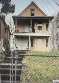 back of property featuring a porch, a balcony, and fence