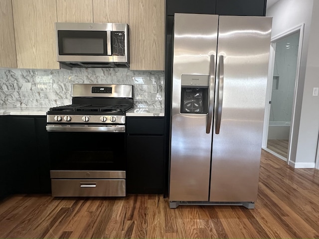 kitchen with dark hardwood / wood-style flooring, light brown cabinetry, decorative backsplash, and stainless steel appliances