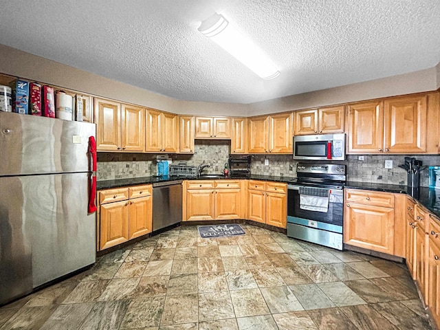 Harmon Cove Tower 426, Secaucus, NJ 07094 - kitchen featuring stainless steel appliances, a textured ceiling, dark countertops, tasteful backsplash, and light stone finish flooring