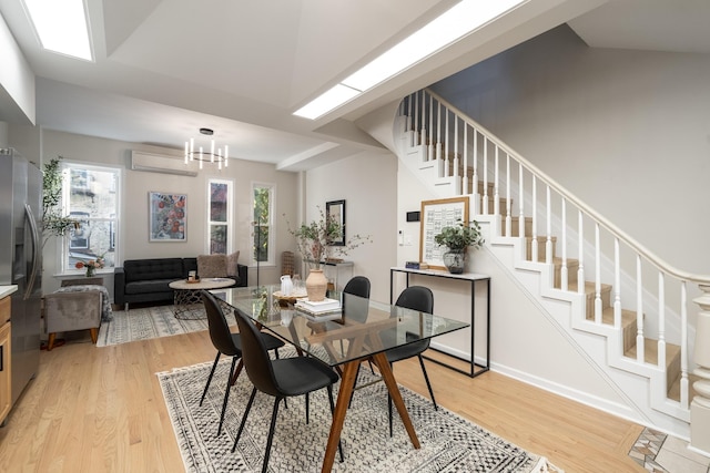 dining space featuring a chandelier, light wood-type flooring, and an AC wall unit