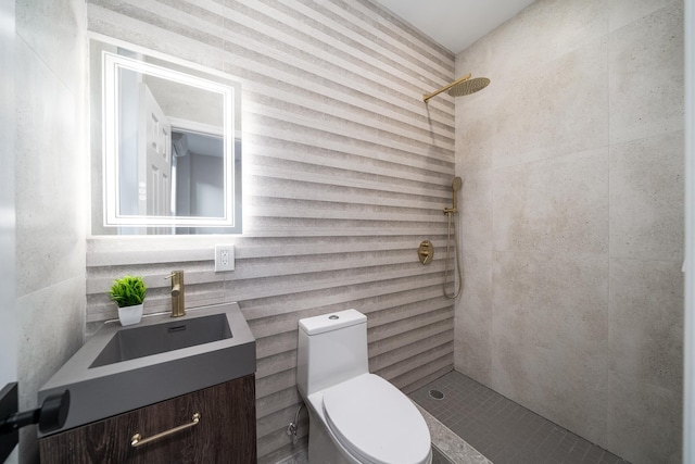 bathroom with tiled shower, vanity, and toilet