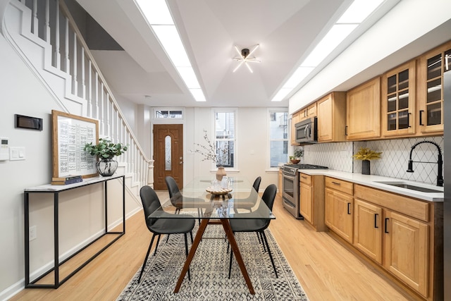 kitchen with decorative backsplash, appliances with stainless steel finishes, sink, and light hardwood / wood-style flooring