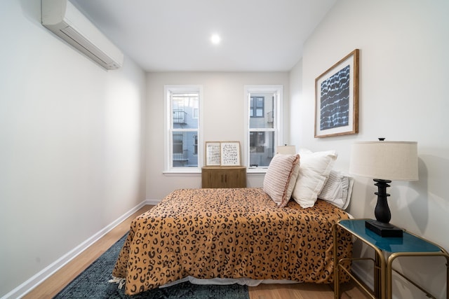 bedroom with hardwood / wood-style flooring and a wall mounted AC