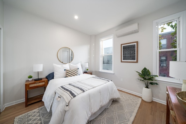 bedroom with a wall mounted AC and light wood-type flooring