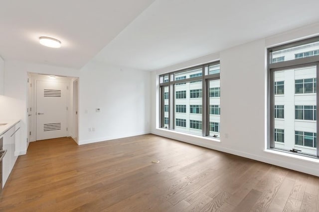 99 Hudson St Unit 601, Jersey City, NJ 07302 - empty room with healthy amount of natural light, light wood-style flooring, and baseboards