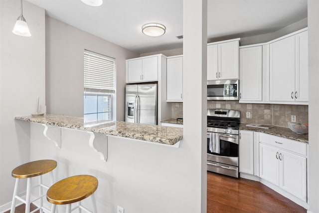 443 2nd St Unit 412, Jersey City, NJ 07302 - kitchen with appliances with stainless steel finishes, light stone counters, a breakfast bar, white cabinets, and tasteful backsplash