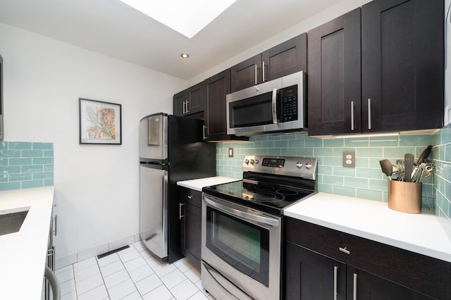 kitchen with decorative backsplash, light countertops, light tile patterned flooring, and stainless steel appliances