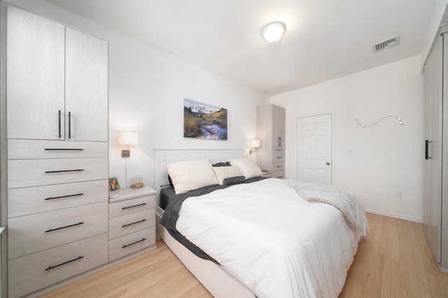 bedroom with visible vents, light wood-style flooring, and baseboards