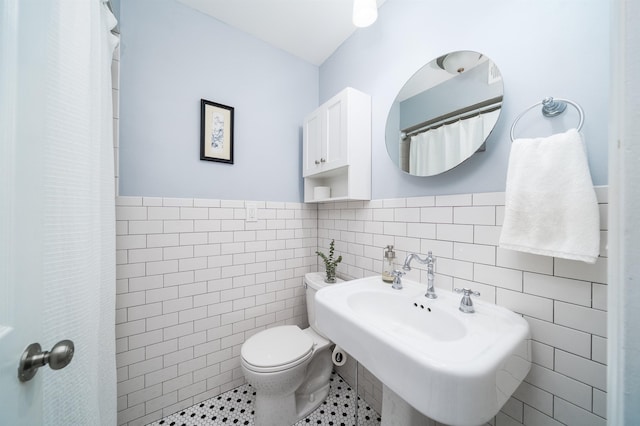 full bath with toilet, a sink, tile walls, wainscoting, and tile patterned flooring