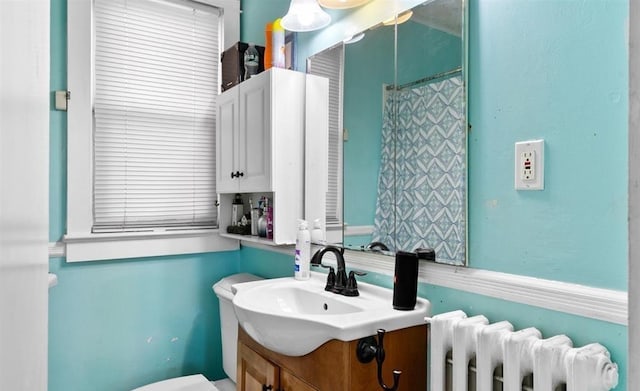 bathroom featuring toilet, vanity, and radiator heating unit