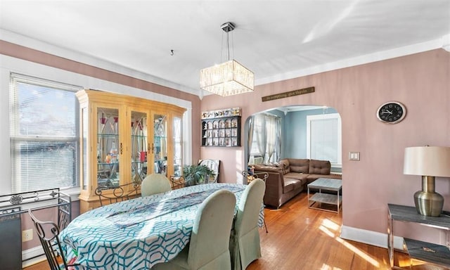 dining area featuring light hardwood / wood-style floors, crown molding, and an inviting chandelier