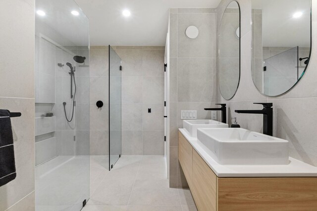 413 Monroe St Unit 200, Hoboken, NJ 07030 - bathroom featuring a walk in shower, tile walls, double vanity, tile patterned flooring, and recessed lighting