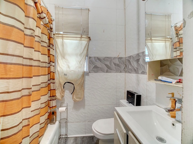 full bathroom with shower / bath combination with curtain, vanity, tile walls, hardwood / wood-style floors, and toilet