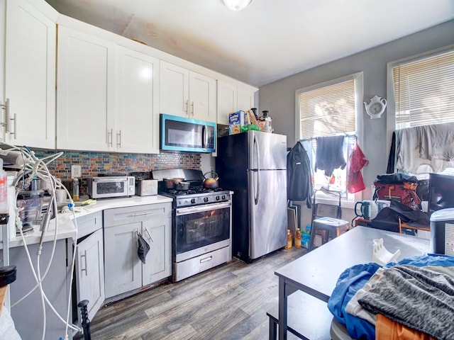 kitchen with decorative backsplash, white cabinetry, stainless steel appliances, and hardwood / wood-style flooring