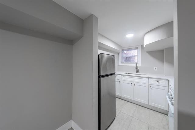 kitchen with sink, stainless steel fridge, white cabinetry, and stove