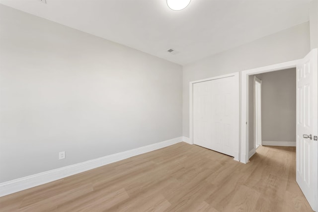 unfurnished bedroom with a closet and light hardwood / wood-style floors