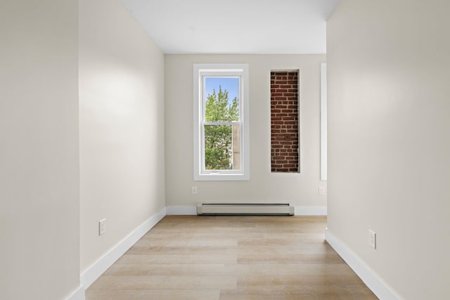 spare room featuring a baseboard radiator, light wood-style flooring, and baseboards