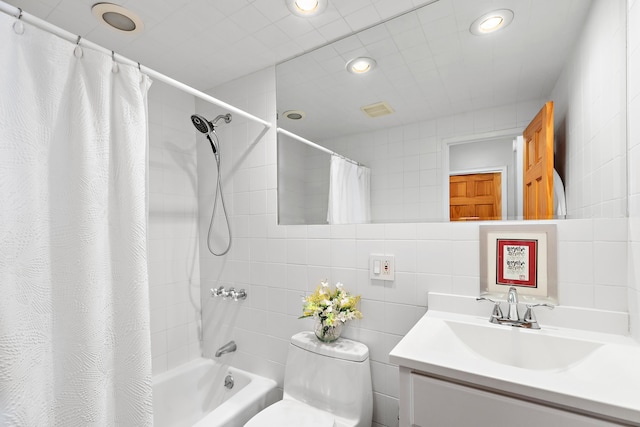 full bathroom featuring toilet, tile walls, shower / bath combo with shower curtain, vanity, and recessed lighting