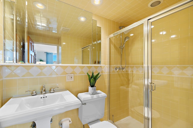 full bath featuring a sink, toilet, tile walls, recessed lighting, and a stall shower