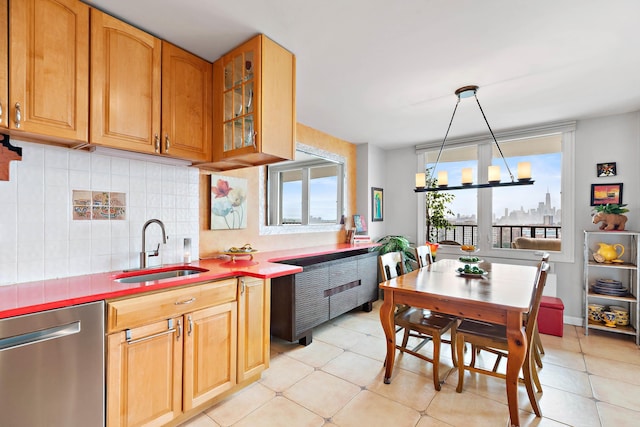 kitchen with light tile patterned floors, glass insert cabinets, a sink, stainless steel dishwasher, and decorative backsplash