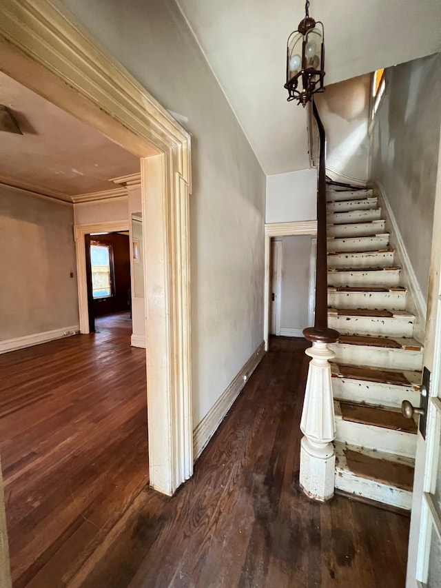 stairs featuring ornamental molding, wood-type flooring, and an inviting chandelier