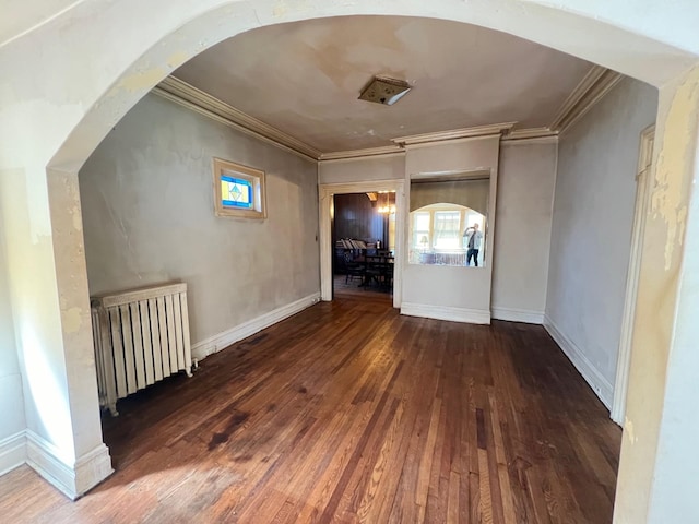 empty room with crown molding, radiator heating unit, and dark hardwood / wood-style flooring