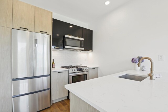 kitchen featuring light wood-style flooring, modern cabinets, appliances with stainless steel finishes, a sink, and backsplash