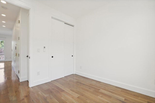 unfurnished bedroom featuring light wood-style floors, baseboards, a closet, and recessed lighting