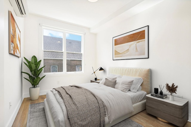 bedroom with baseboards, wood finished floors, and a wall mounted air conditioner