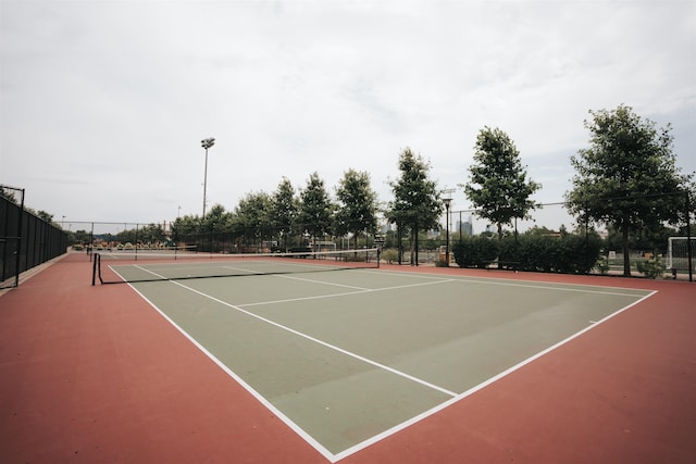 view of tennis court featuring community basketball court and fence