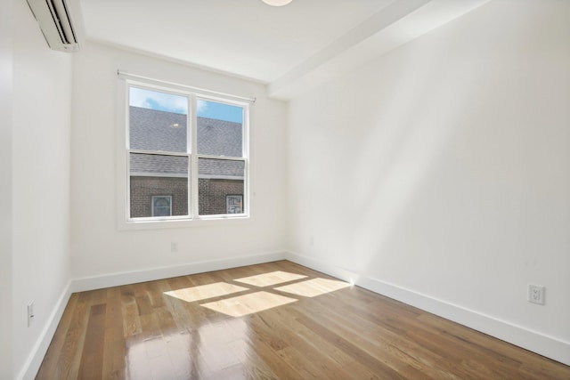 spare room featuring a wall mounted AC and light hardwood / wood-style floors