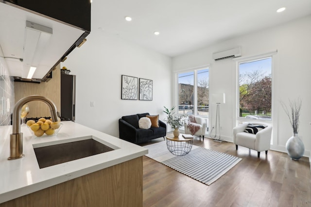 living room featuring wood finished floors, recessed lighting, and a wall unit AC