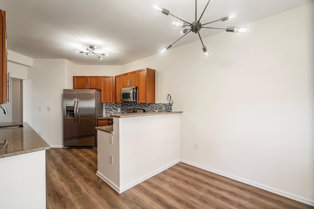 kitchen with dark wood-style flooring, a sink, stainless steel appliances, tasteful backsplash, and brown cabinets