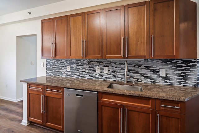 kitchen with tasteful backsplash, dark wood finished floors, dark stone counters, stainless steel dishwasher, and a sink