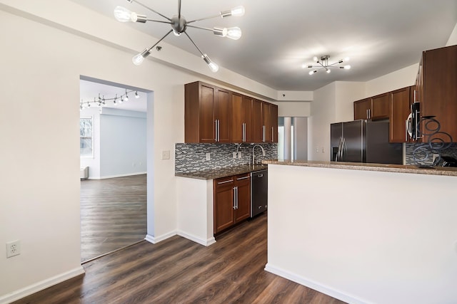 kitchen featuring backsplash, dark wood-style flooring, dark stone countertops, stainless steel appliances, and a sink